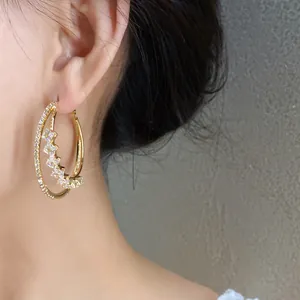 Close-up of elegant double-layered gold hoop earrings with sparkling CZ stones