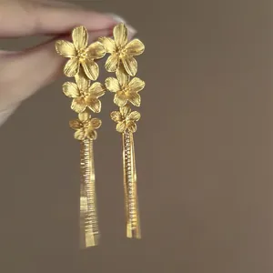 Close-up of gold French vintage floral earrings with textured petals and long tassels.