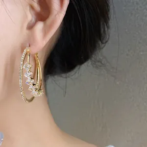Close-up detail of 18k gold plated double-layer hoop earrings with sparkling cubic zirconia