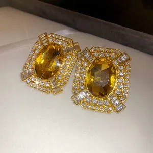 Close-up detail of luxurious gold-tone earrings with large yellow oval stones