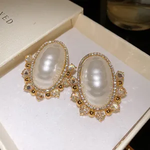 Close-up of elegant oval zircon earrings with silver needles in a gift box