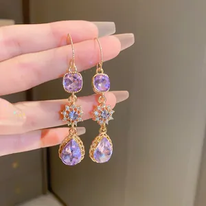 Detailed view of long purple teardrop dangle earrings with sparkling star zircon accents.