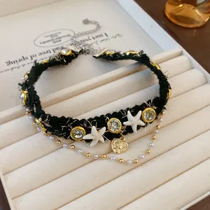Close-up of black tweed choker with rhinestone stars and delicate pearl chain layers
