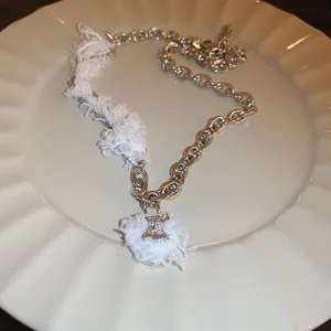 Detailed view of white fuzzy choker necklace with silver chain and rhinestone pendant