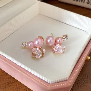 Macro view of elegant pink pearl flower earrings with rhinestones in a gift box.