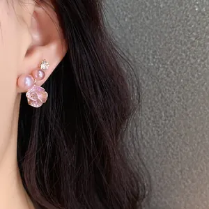 Close-up of pink pearl flower stud earring with rhinestone detail on an Asian model's ear