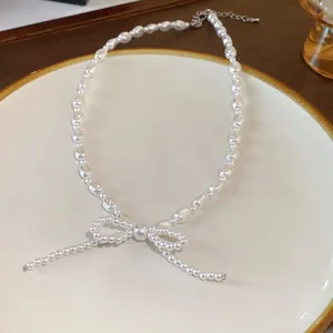 Detailed view of an elegant white pearl necklace with a delicate bow-knot pendant.