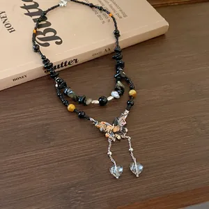 Close-up detail of a bohemian double-layer butterfly necklace with heart pendants on vintage book