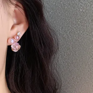 Close-up of elegant floral stud earrings with pink pearls and sparkling zircon details