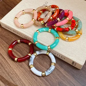 Detailed view of colorful acrylic tube bracelets stacked on a vintage book