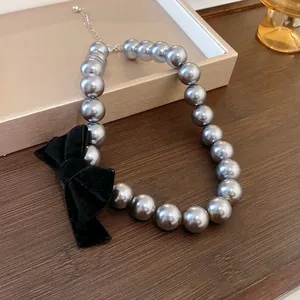 Detailed view of grey pearl necklace with elegant black velvet bow and silver lobster clasp.