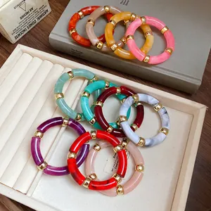 Detailed close-up of iridescent acrylic round patchwork bracelets in a white jewelry tray.