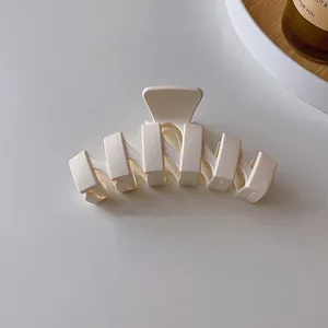 Gros plan d'une pince à cheveux minimaliste crème ondulée avec une finition mate texturée