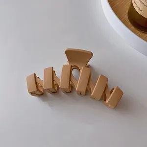 Vue détaillée montrant la texture d'une pince à cheveux mate en forme de vague, caramel