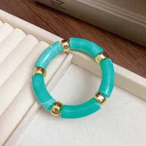 Detail of green iridescent acrylic bracelet with gold metal spacers on jewelry tray