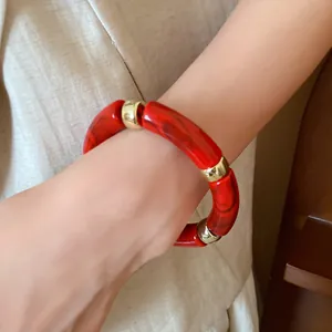 Detail view of red acrylic iridescent tube bracelet with gold metal spacer beads