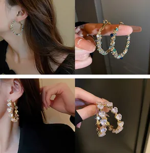 Dettaglio di orecchini a cerchio con perline colorate e zirconia a cuore per donna
