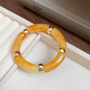 Detailed view of amber iridescent acrylic bracelet with gold-toned metal spacers