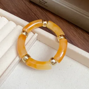 Close-up detail of an orange marbled acrylic segmented bracelet with gold metal spacers.