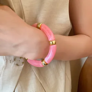 Detailed close-up of a pink marbled acrylic tube bracelet with elegant gold spacers