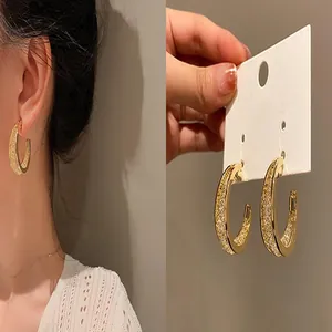 Eleganti orecchini a cerchio a C color oro con dettagli scintillanti per moda femminile.