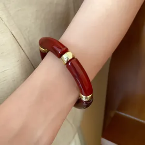 Detail of retro red marbled acrylic segmented bracelet with gold accents on wrist