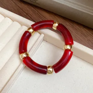 Macro detail of red marbled acrylic segments and golden metal spacers on this retro bracelet