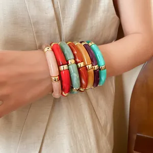Vibrant stack of colorful acrylic tube bead bracelets with gold metal spacers on wrist