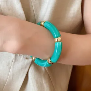 Close-up of a turquoise acrylic marble tube bracelet with gold spacers on a wrist
