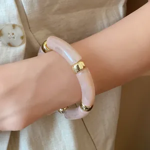 Close-up of retro acrylic iridescent spliced bracelet with gold spacers on wrist