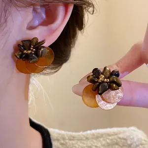 Orecchini a fiore vintage con occhio di tigre e dischi di conchiglia su una modella
