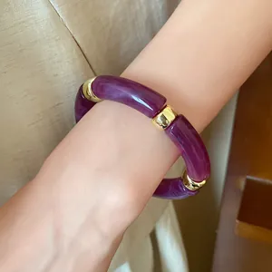 Close-up detail of a purple marbled acrylic tube bracelet with gold metal spacers worn on wrist