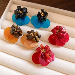Primo piano di orecchini vintage a fiore con pietre occhio di tigre e petali di conchiglia