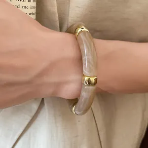 Close-up of a stylish acrylic iridescent bracelet with marble texture and gold accents