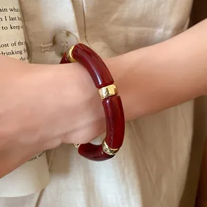Close-up of retro burgundy acrylic spliced bracelet with gold metal spacers on wrist