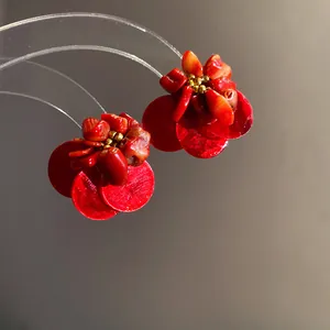 Vista macro dettagliata di orecchini vintage a forma di fiore realizzati in conchiglia rossa.