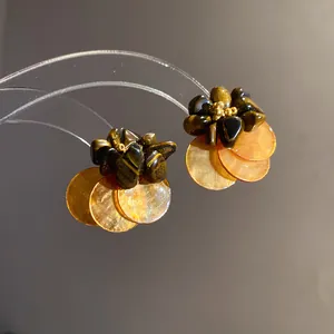 Dettaglio orecchini a fiore vintage con occhio di tigre e dischi di conchiglia