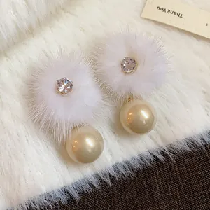 Primo piano di eleganti orecchini a pompon in peluche con zirconi e dettagli in perla