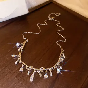 Detail of a sparkling gold-tone rhinestone waterdrop branch necklace on wood