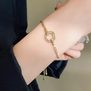 Detail of a gold adjustable bracelet with a pave-set rhinestone circular centerpiece.