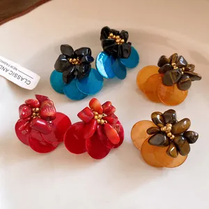Primo piano dettagliato di orecchini vintage a fiore con occhio di tigre e petali in conchiglia