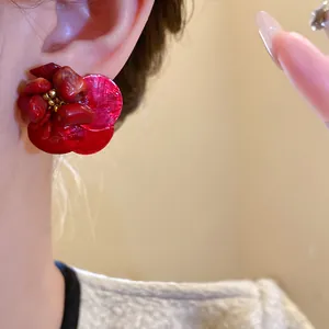 Dettaglio ravvicinato di orecchini vintage a fiore in conchiglia rossa sul lobo