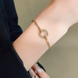 Detail shot of an adjustable gold-tone bracelet with a sparkling rhinestone ring on a wrist.