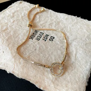 Close-up detail of a gold adjustable bracelet with a sparkling rhinestone circle design