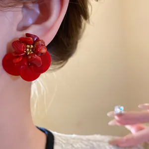 Primo piano di orecchini a fiore in conchiglia rossa con dettagli in pietra vintage.