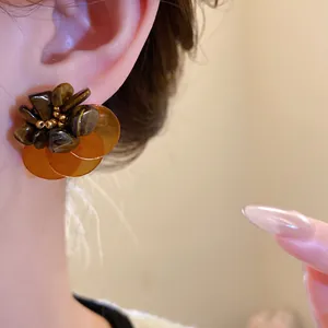 Primo piano di orecchini vintage con occhio di tigre e petali di conchiglia ambra
