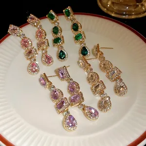 Orecchini pendenti geometrici in stile vintage con strass colorati su un piatto bianco