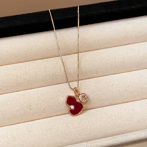 Close-up of red enamel gourd pendant with sparkling zircon accents on delicate gold chain