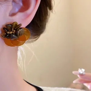 Primo piano di orecchini vintage a fiore con pietra occhio di tigre e petali di conchiglia