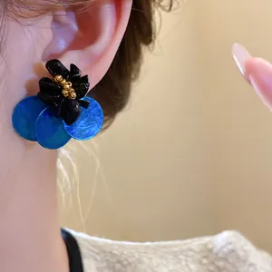 Dettaglio orecchini vintage con fiori in conchiglia blu, un elegante gioiello chic